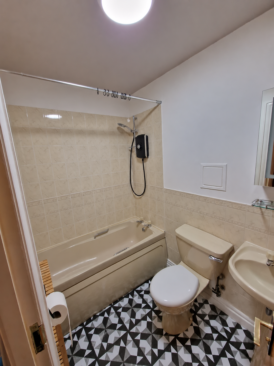 Bathroom showing the bath, shower, toilet, basin and patterned vinyl floor
