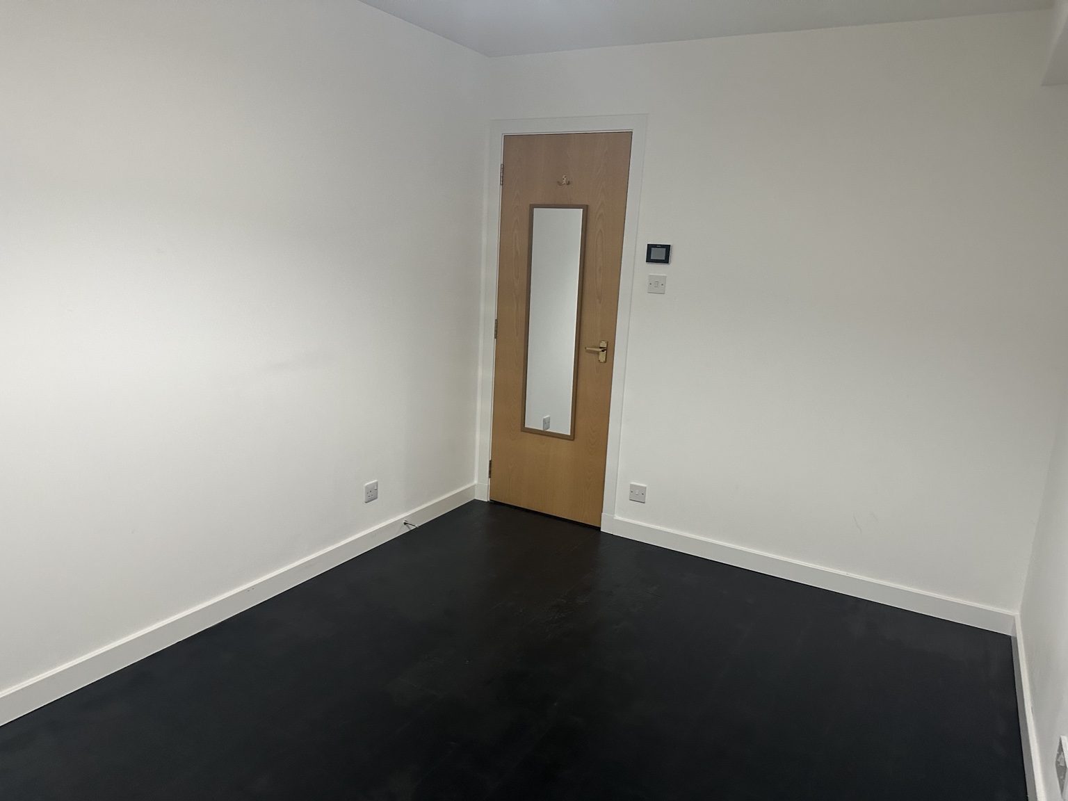 Reverse view of empty Bedroom 2 showing the doorway and charcoal flooring