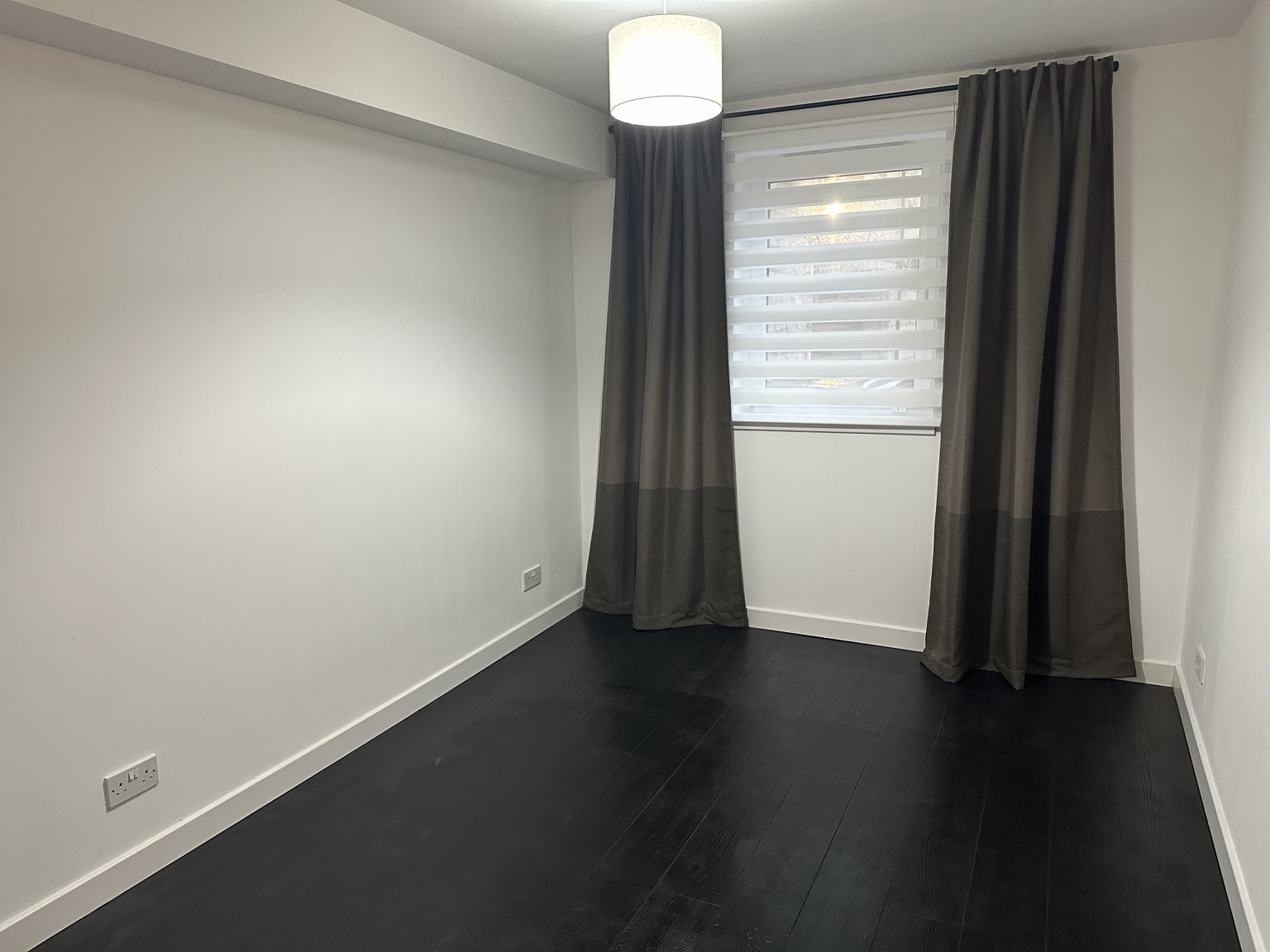 Empty Bedroom 2 facing the window, with grey curtains, fitted blinds and charcoal flooring